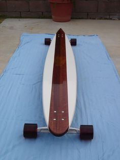 a wooden surfboard sitting on top of a blue blanket next to a potted plant