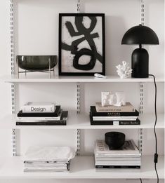 a white book shelf with books on it and a black lamp next to the shelves