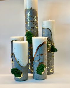 four candles with moss growing on them sitting next to each other