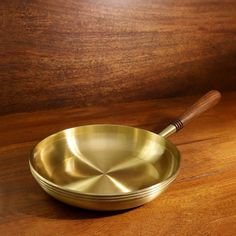 a brass frying pan on a wooden table