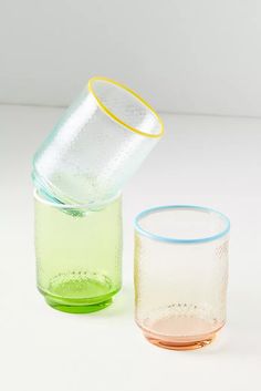 two glasses sitting next to each other on a white surface with one glass half filled with water and the other half empty