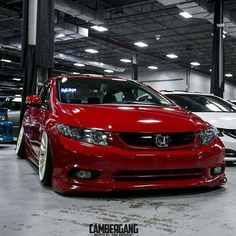 a red car parked in a garage next to other cars