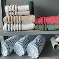 towels are stacked on top of each other in a row, along with rolls of toilet paper