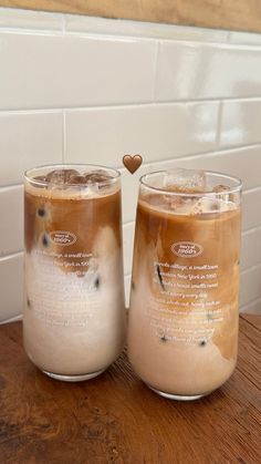 two glasses filled with liquid sitting on top of a wooden table