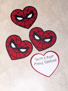 three heart shaped stickers with spiderman faces on them, one says you're a super friend valentine