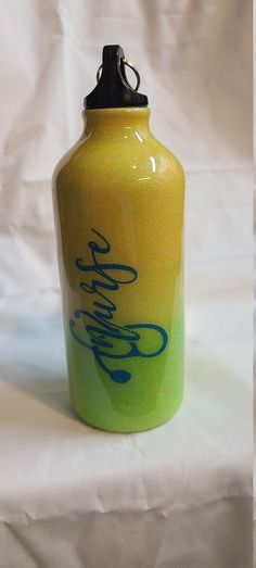 a yellow and green water bottle sitting on top of a white sheeted tablecloth