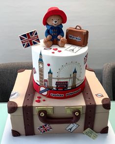 a cake with a teddy bear sitting on top of it and suitcases around it