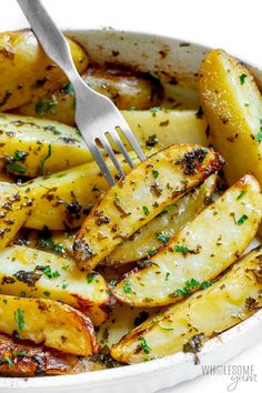 a white bowl filled with cooked potatoes covered in seasoning and topped with a fork