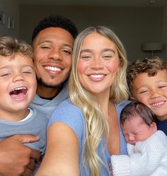 a man, woman and two children are smiling for the camera with their arms around each other