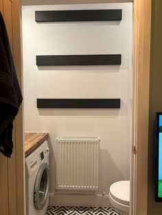 a washer and dryer sitting in a bathroom next to a wall mounted flat screen tv