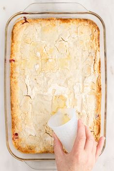 a person holding a napkin in front of a baking dish