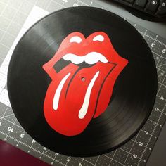 a record with the rolling stones logo on it sitting next to a keyboard and mouse