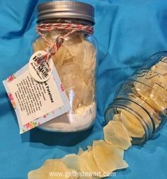 a glass jar filled with lots of white stuff next to a tag on a blue cloth