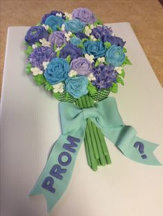 a bouquet of blue and purple flowers on top of a white box with a ribbon