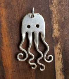 an octopus shaped metal object hanging on a wooden surface