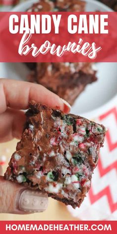 a hand holding up a piece of candy cane brownies in front of a plate