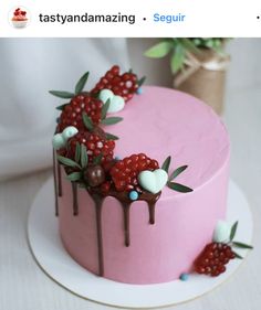 a pink cake decorated with berries and chocolate drips