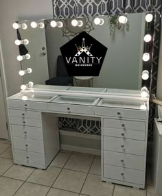 vanity with lighted mirror and drawers in front of wallpapered background that says vanity