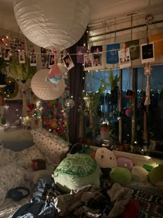 a room with lots of stuffed animals and pictures hanging from the ceiling over it's bed