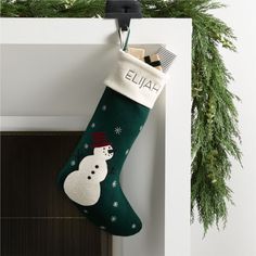 a green christmas stocking with a snowman on it hanging from a door handle