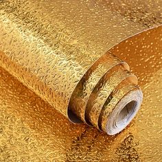 a roll of gold metallic foil on top of a table with water droplets all over it