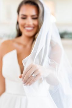 a woman in a wedding dress is holding her veil