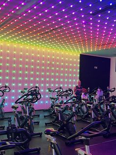 a man standing next to a row of exercise bikes in front of a colorful wall