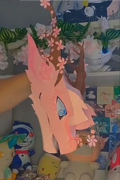 a person holding up a paper cut out of a pink unicorn's head with flowers on it