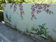 a wall with flowers painted on it and birds in the grass next to it,