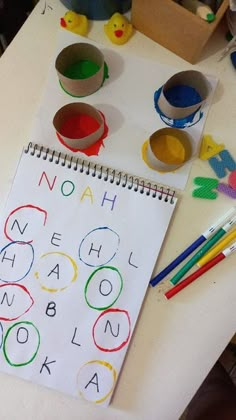 a child's workbook with letters and numbers drawn on it next to colored pencils