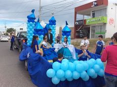 some people are standing in the back of a car with balloons on it and one person is holding a cell phone