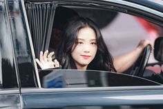 a woman sitting in a car waving out the window