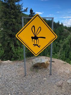 a yellow sign sitting on top of a rocky hillside