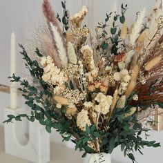 a vase filled with lots of different types of flowers next to a candle on top of a table