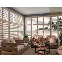 a living room filled with furniture and large windows covered in shuttered glass doors that look out onto the ocean