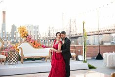 a man and woman standing next to each other in front of a table with flowers on it