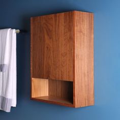 a wooden cabinet hanging on the wall next to a towel rack