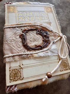 an old book with rope and beads on it sitting on the floor next to a rug