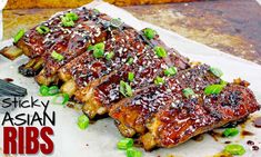 ribs covered in sauce and green onions on top of a piece of parchment paper next to a fork