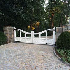 a driveway gate with brick pavers and stone pillars