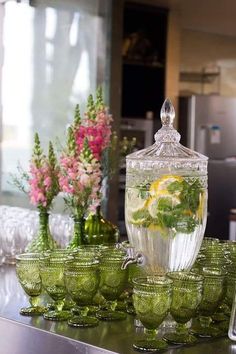 there are many green glass bowls on the counter with lemons and water in them