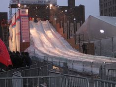 people are standing in front of a slide at an event with snow on the ground