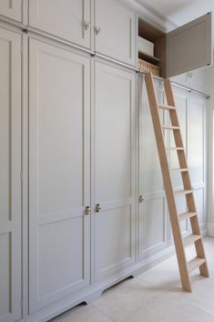 a ladder leaning up against the wall in a room with white cupboards and drawers