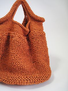 an orange knitted purse sitting on top of a white table