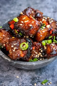 a bowl filled with meat and vegetables covered in sesame seeds on top of a table