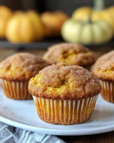 several muffins on a white plate with pumpkins in the backround