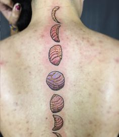 the back of a woman's neck with five seashells on it