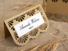 two brown and white place cards sitting on top of burlocked linens