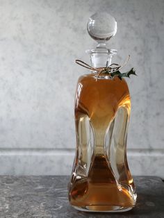 a glass bottle filled with liquid sitting on top of a stone table next to a plant