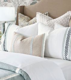 a neatly made bed with white and blue pillows